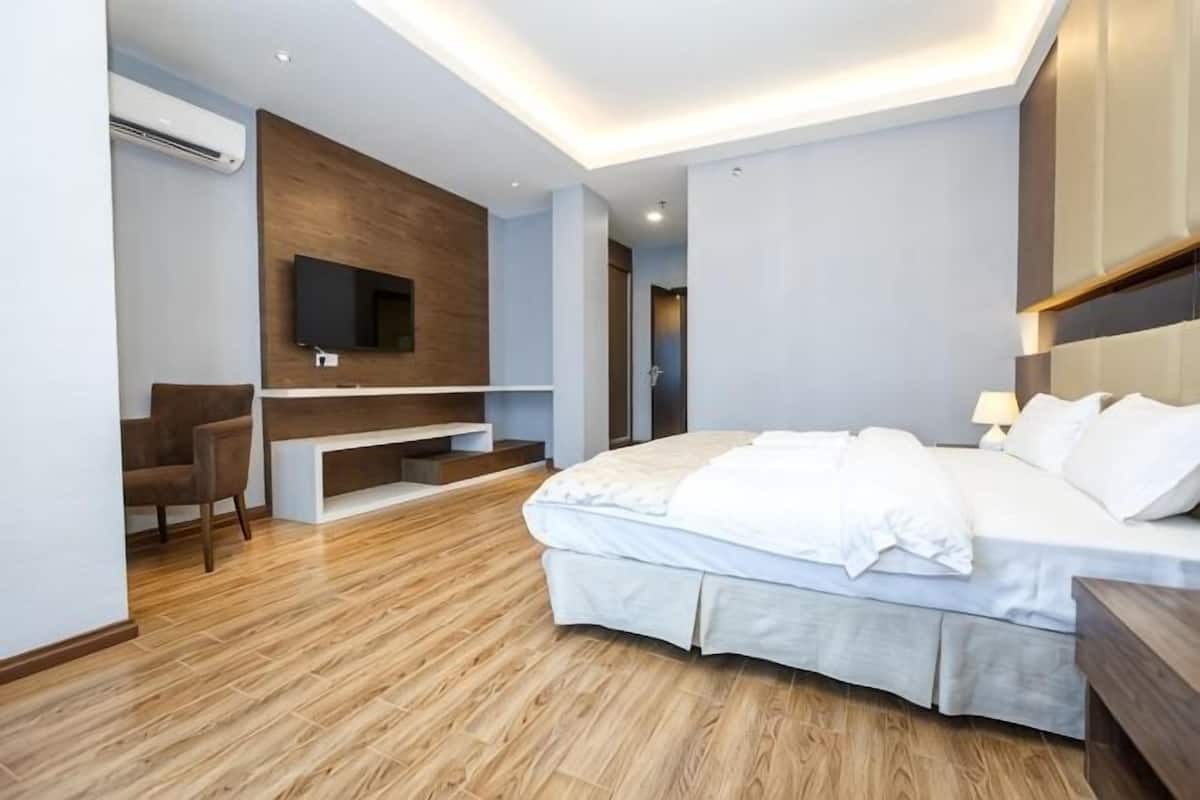 A modern hotel room with a bed, a TV mounted on a wall, a desk, and a chair.