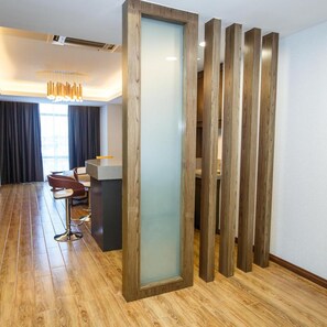 A modern hotel room with a wooden floor, a desk with a computer, a sofa, and a large window with curtains. - Lintas Platinum Hotel (Kota Kinabalu)