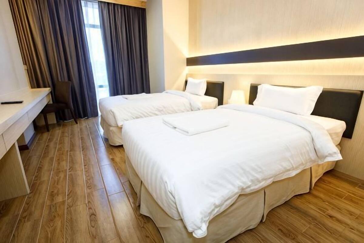 A hotel room with two beds, a desk, and a chair.