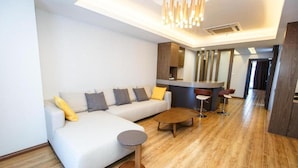A modern living room with a sofa, coffee table, and bar stools. - Lintas Platinum Hotel (Kota Kinabalu)