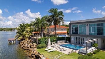 Una propiedad frente al mar con piscina, mobiliario exterior y vista al agua.