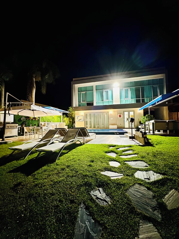 A modern building with a pool, outdoor seating, and a well-lit entrance. - VILLA JOYUDA (Cabo Rojo)