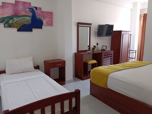 Habitación de hotel con dos camas, un escritorio de madera, un televisor y una pintura de un pavo real en la pared.
