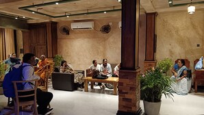 A group of people seated in a room with wooden furniture, air conditioning units, and potted plants. - La Cozy Hotel & Restaurant (Negombo)