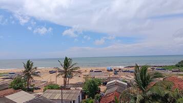 Ein Küstendorf mit Strandhütten, Palmen und traditionellen Häusern mit roten Ziegeldächern.