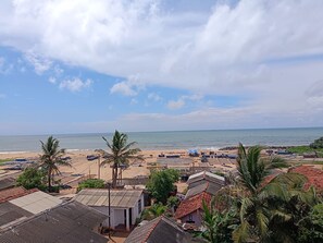 Un pueblo costero con cabañas de playa, palmeras y casas tradicionales con techos de tejas rojas.