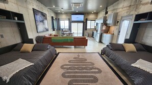 A modern hotel room with two beds, a central sofa, a kitchen area, and a large window providing a view. - Cigar Mountain House (Brewster County)