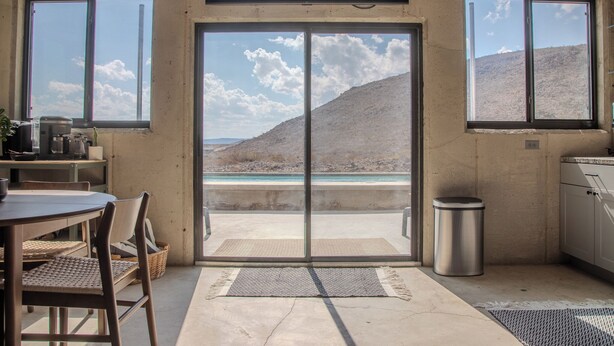 A kitchen with a large sliding glass door leading to a balcony with a view of a mountainous landscape. - Cigar Mountain House (Brewster County)