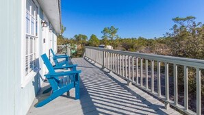 A wooden deck with blue chairs and a railing, overlooking a natural landscape.