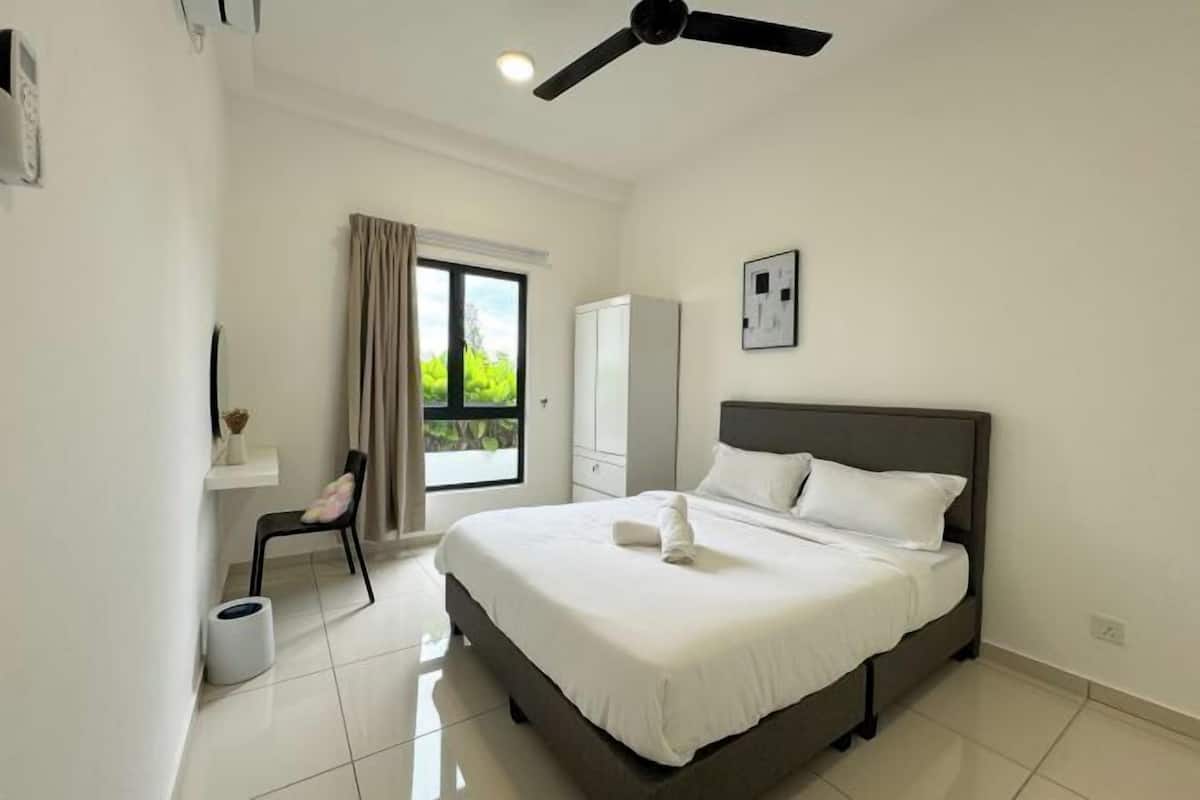 A modern bedroom with a large bed, a ceiling fan, a window with curtains, and a view of greenery outside.