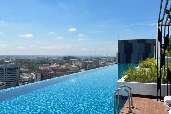 A rooftop infinity pool with a city view, a modern building, and a small garden area. - The Horizon Ipoh By Iconique Espace (Ipoh)