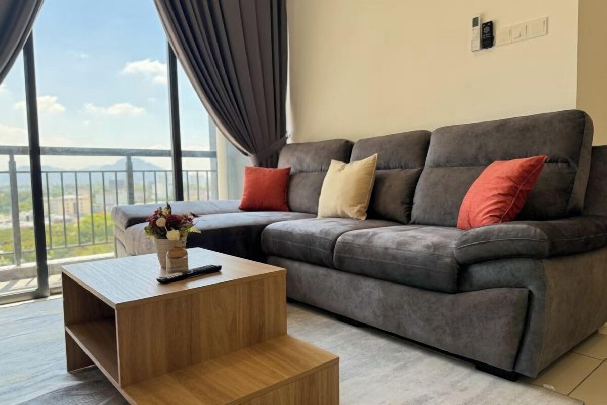 A modern living room with a grey sectional sofa, a wooden coffee table, and a view of a balcony.