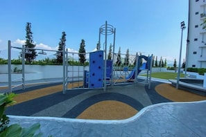 A playground with a slide, climbing structures, and a fenced area.