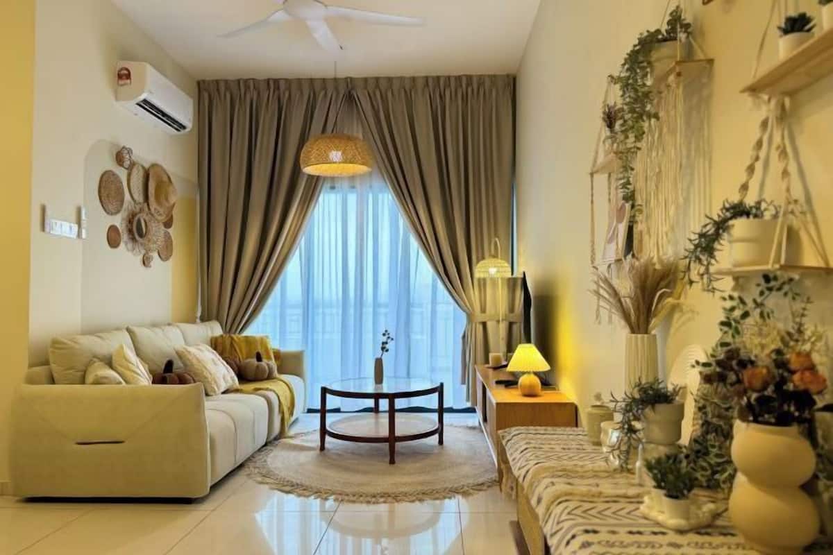 A modern living room with a sofa, a round coffee table, and a lamp. There are curtains, a ceiling fan, and wall-mounted decor.