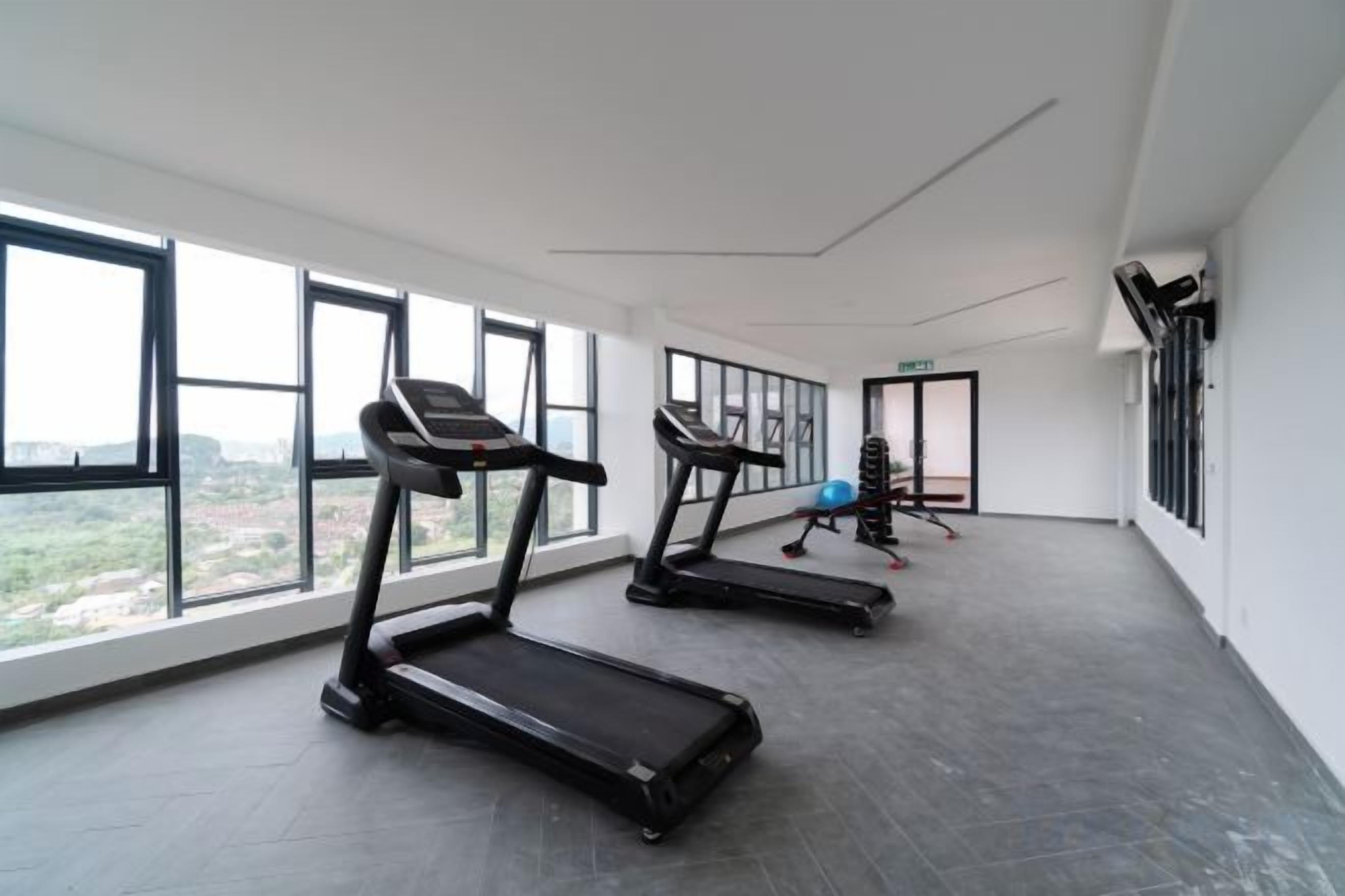 A gym with treadmills and exercise equipment, large windows, and a view of the outdoors.