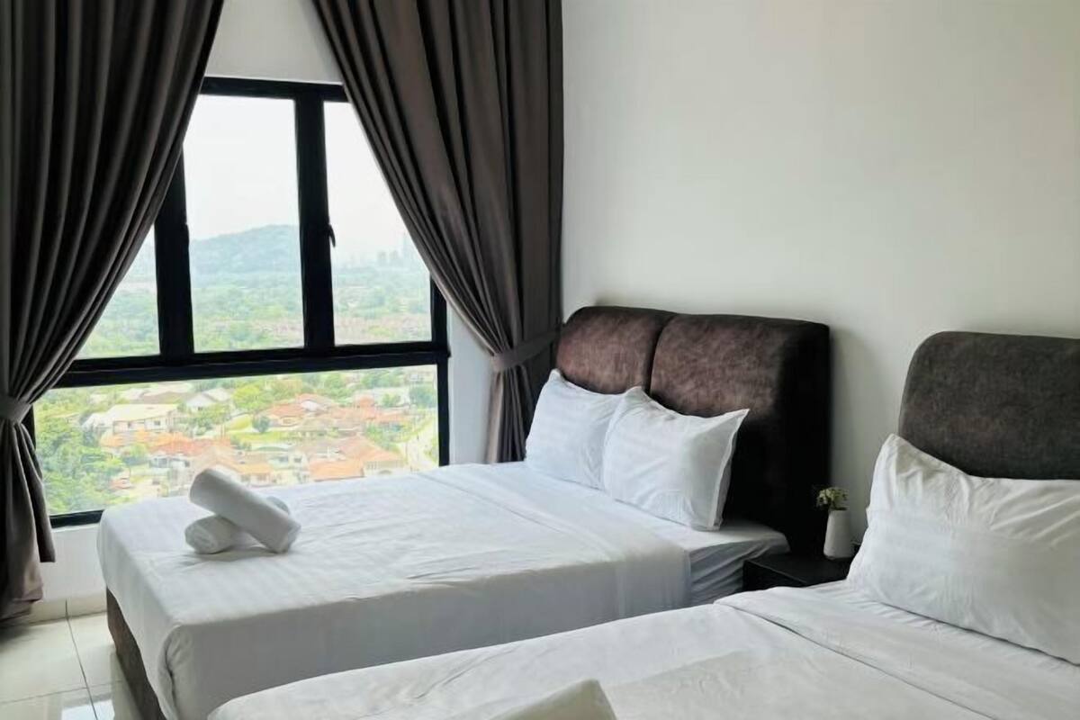 A hotel room with two beds, a large window with curtains, and a view of a cityscape.