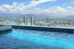Una piscina con vistas a un paisaje urbano y montañas al fondo.