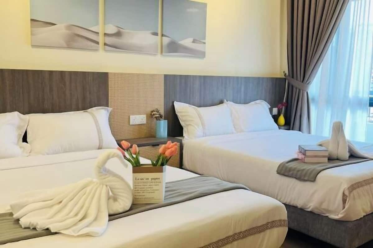 Two beds with white linens, a wall-mounted artwork, a vase with flowers, and a window with curtains.