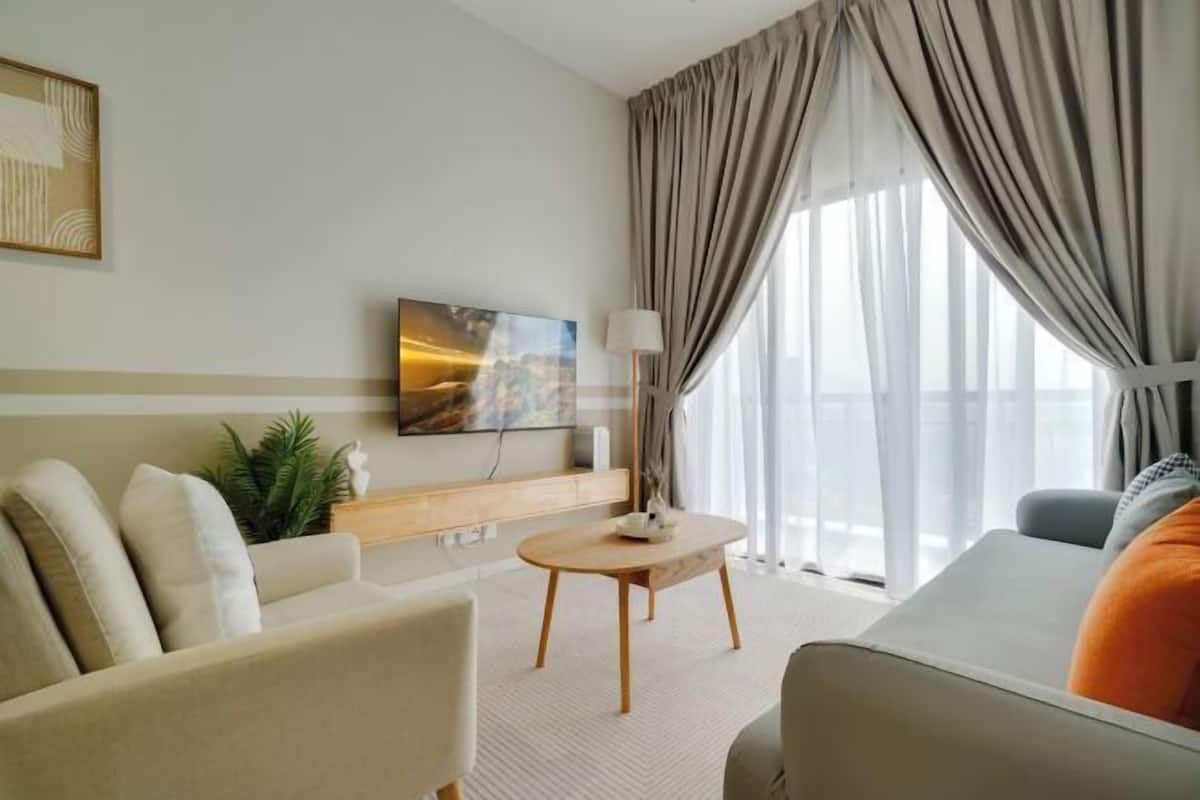 A modern living room with a sofa, a coffee table, and a TV mounted on the wall.
