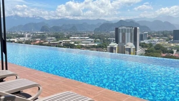 A rooftop infinity pool with a cityscape view, including mountains and buildings.