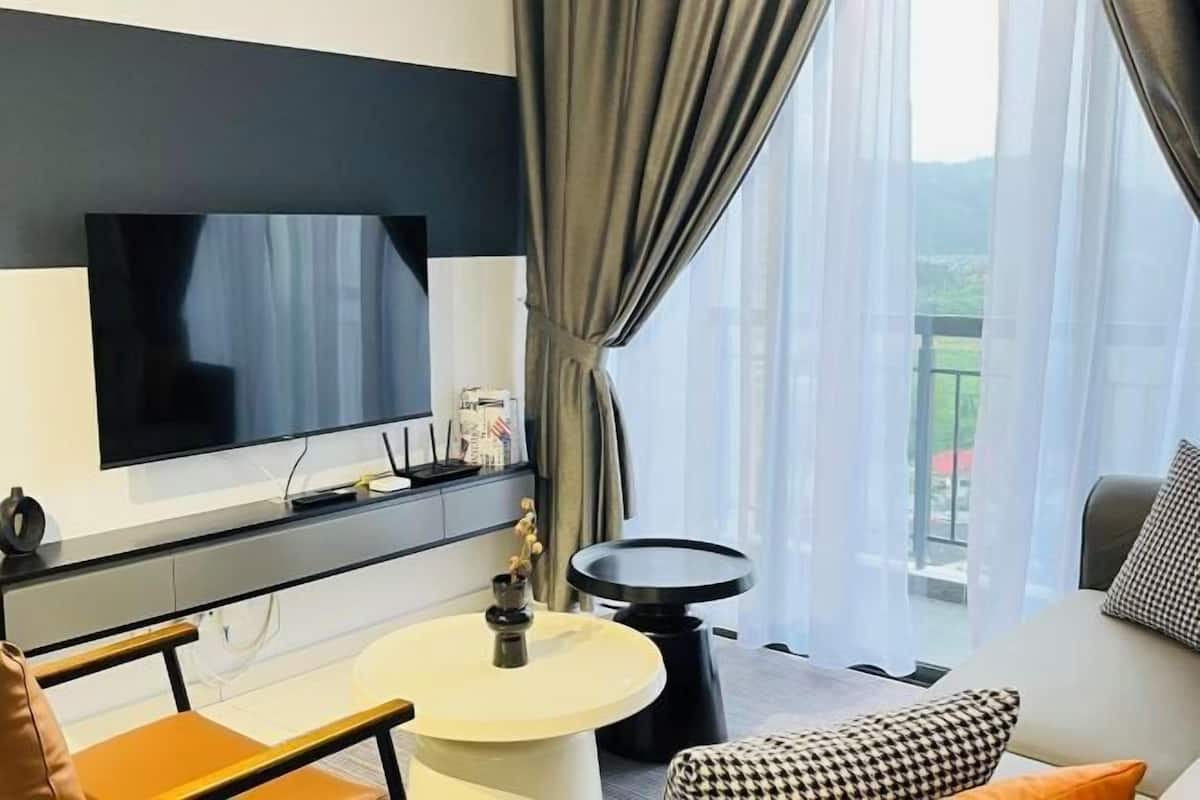 A modern living room with a flat-screen TV, a round coffee table, a sofa, and a balcony view.