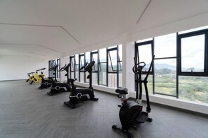 Uma academia com equipamentos de ginástica e amplas janelas.