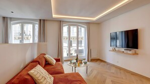 Ein modernes Wohnzimmer mit einer Couch, einem Couchtisch und einem an der Wand befestigten Fernseher.