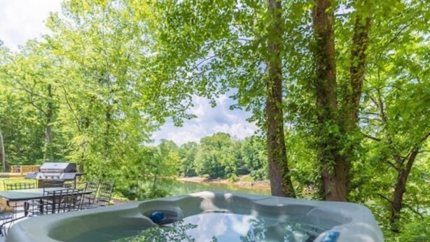 A hot tub surrounded by lush greenery and a view of a river. - The Enclave at Cumberland (Albany)