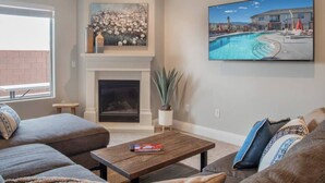 A living room with a fireplace, a poolside view painting, and a sofa. - Zion's Premier Getaway for the entire family!  (Hurricane)