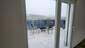 A balcony with a view of solar panels and a chair. - Modern Villa by the River – Peace, Comfort, and 3 Terraces (Koblenz)