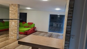A room with a green sofa set, a wooden table, and a brick wall. - Modern Villa by the River – Peace, Comfort, and 3 Terraces (Koblenz)