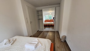 A bedroom with a bed, a wardrobe, and a mirror reflecting a room with a bed and a window. - Modern Villa by the River – Peace, Comfort, and 3 Terraces (Koblenz)