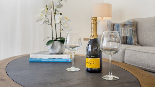 Une bouteille de Prosecco Valdo sur une table, avec deux verres à vin.