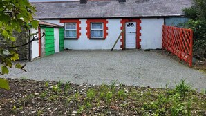 A house with a gravel driveway, a red gate, and a green shed.
