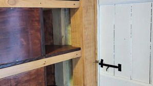 A wooden shelving unit with multiple shelves against a white door with a black handle.