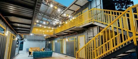A spacious industrial-style interior with a staircase, a sofa, and a high ceiling with exposed beams.