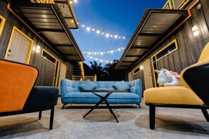An outdoor seating area with a sofa and chairs, string lights, and a small table. - 7 Inn Semporna (Semporna)
