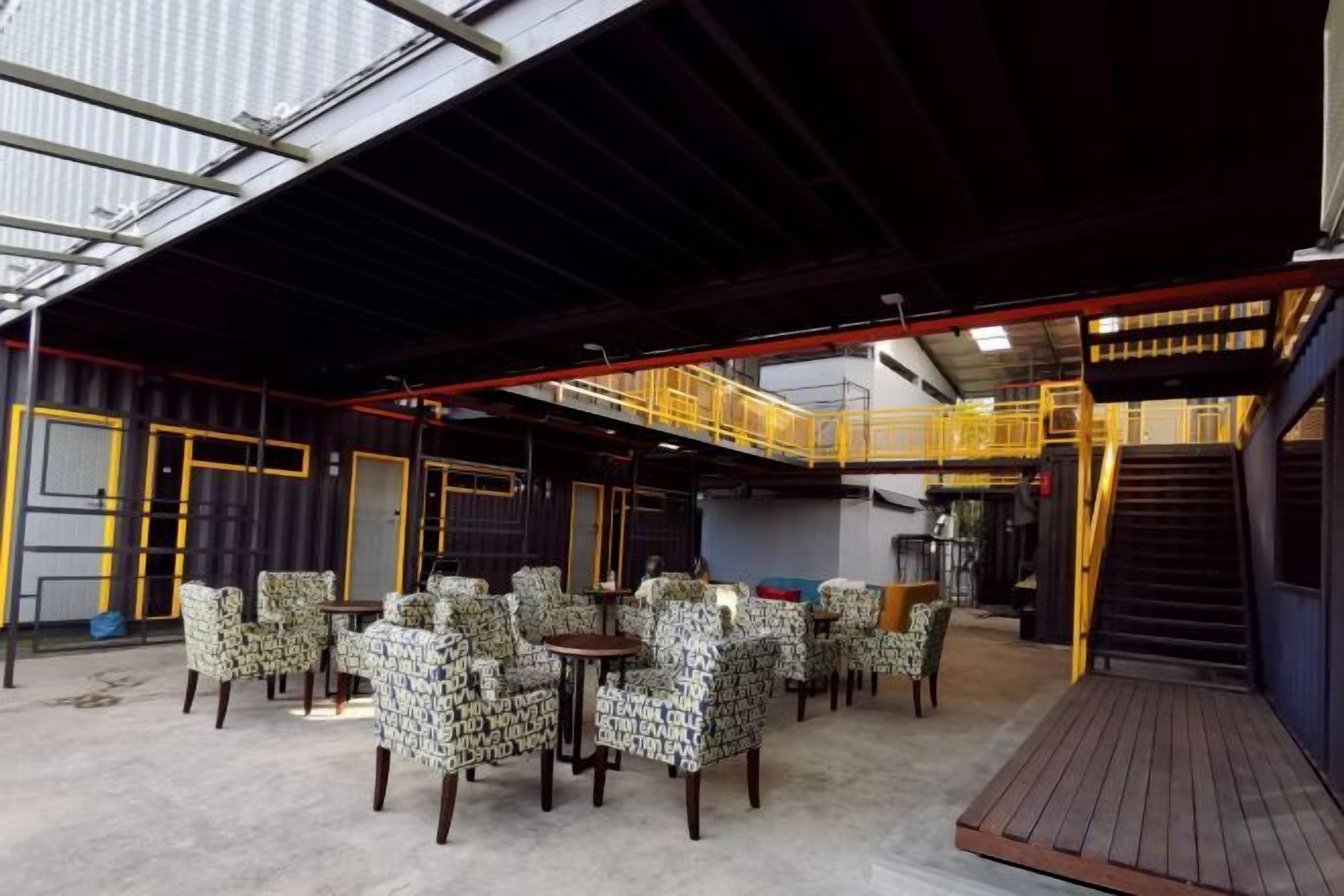 A covered outdoor seating area with tables and chairs, a staircase, and a metal roof structure.