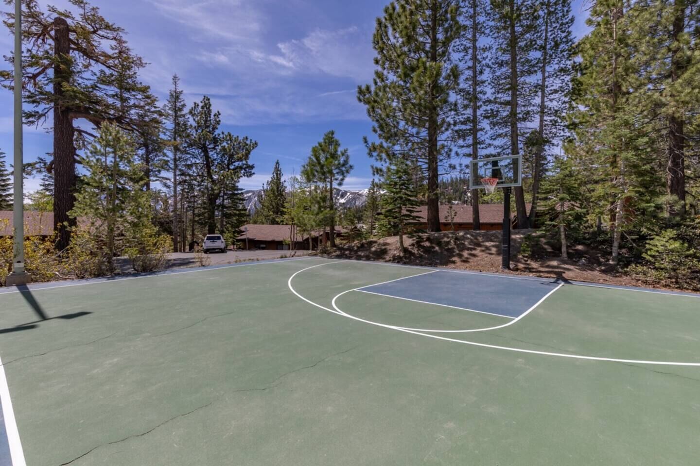 An outdoor basketball court surrounded by trees and buildings.