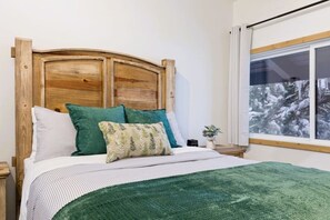 Ein Bett mit hölzernem Kopfteil, einer grünen Tagesdecke und Kissen.