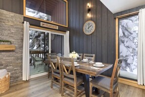 A dining area with a wooden table, chairs, and a clock on the wall.
