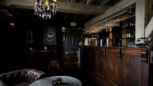 Zona de bar con una mesa redonda, sillas de cuero y una barra de madera.