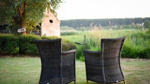 Two wicker chairs in an outdoor setting with a stone structure in the background. - Ter Polders (Damme)