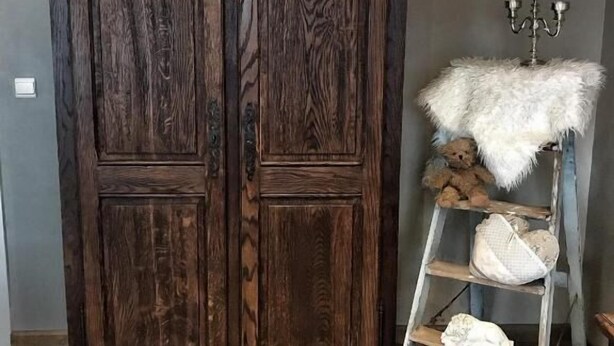 Ein großer, zweitüriger Holzschrank mit einer Leiter davor.