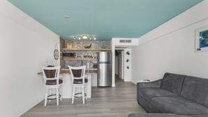 A modern kitchen with a stone backsplash, a stainless steel refrigerator, and a dining area with white chairs. - Amazing Ocean Front Property on Daytona Beach with amazing views & full kitchen (Daytona Beach)