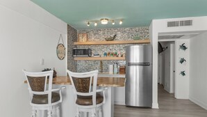 A compact kitchen with a central island, white cabinetry, and a stainless steel refrigerator. - Amazing Ocean Front Property on Daytona Beach with amazing views & full kitchen (Daytona Beach)