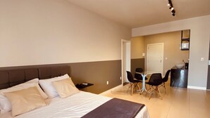 Une chambre d’hôtel moderne avec un grand lit, un petit bureau et un coin repas avec des chaises.
