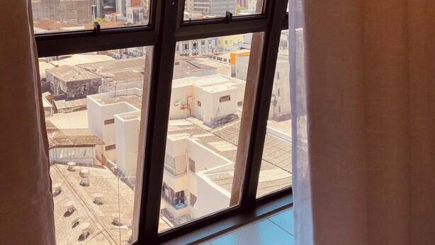 Une vue à travers une fenêtre donnant sur un paysage urbain, avec des bâtiments et un ciel dégagé.