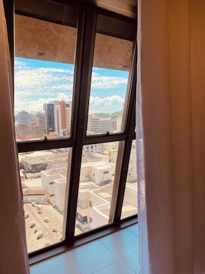 A view through a window with a view of a cityscape, including buildings and a clear sky. - Loft On (Joinville)