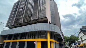 Un bâtiment moderne à la façade incurvée, doté de grandes fenêtres et agrémenté d’une touche de couleur jaune.